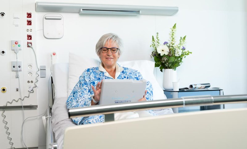 Patientenkamer-eenpersoonskamer-vrouw-in-met-bed-met-tablet