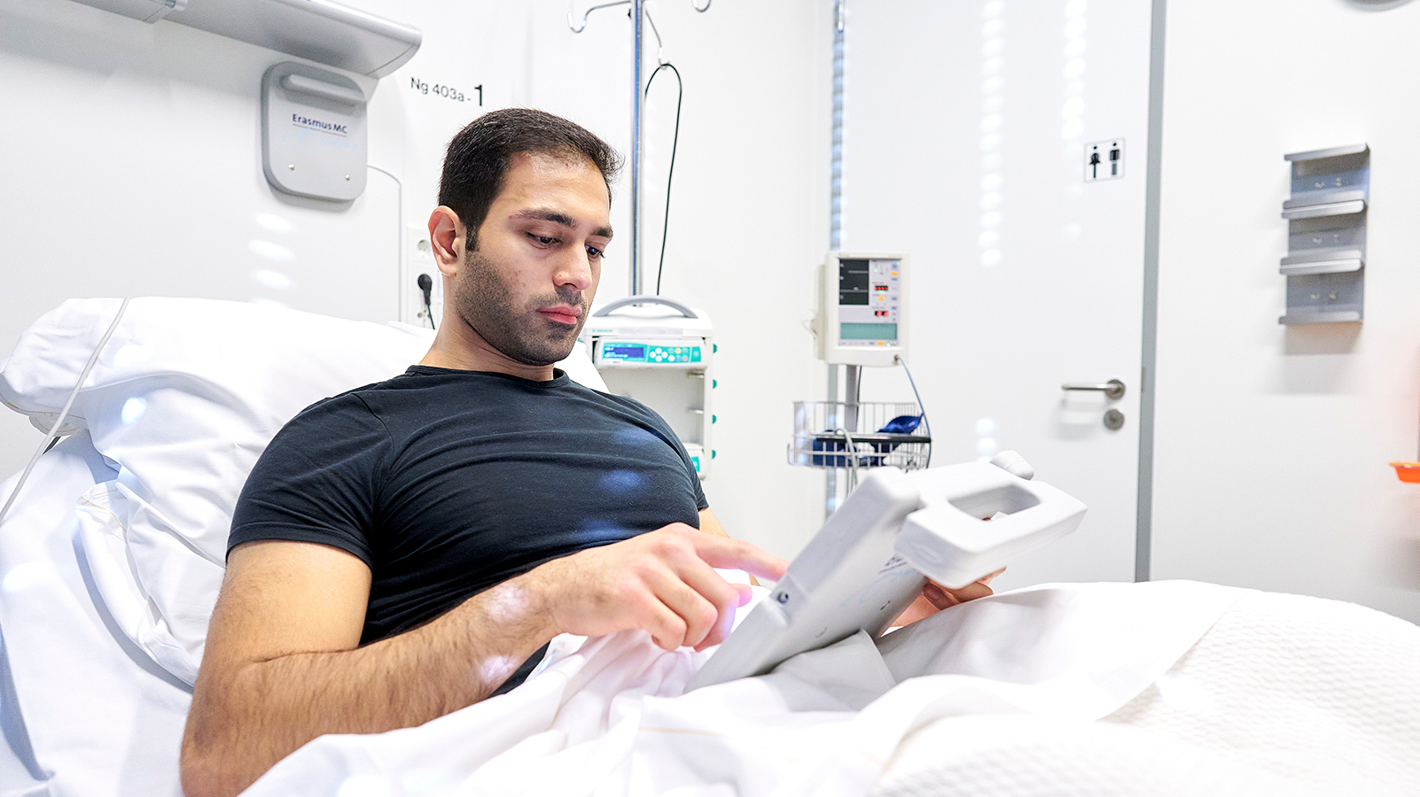 Patiënt in bed gebruikt de Erasmus MC-tablet