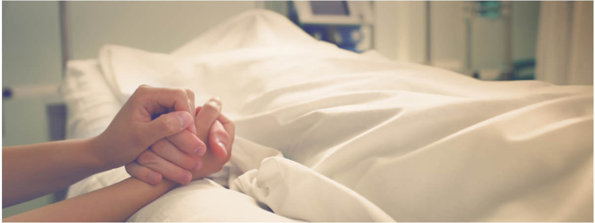 Handen aan bed bij patient onder laken