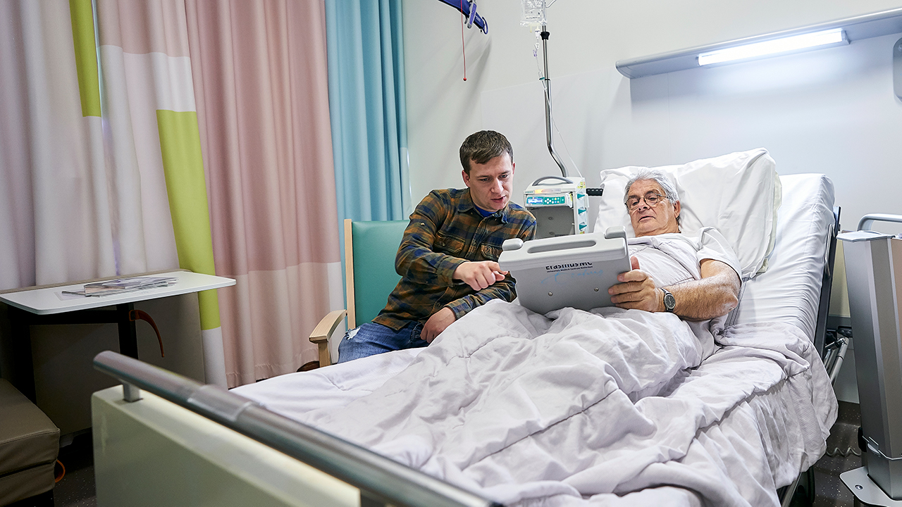 Patient in ziekenhuisbed met tablet