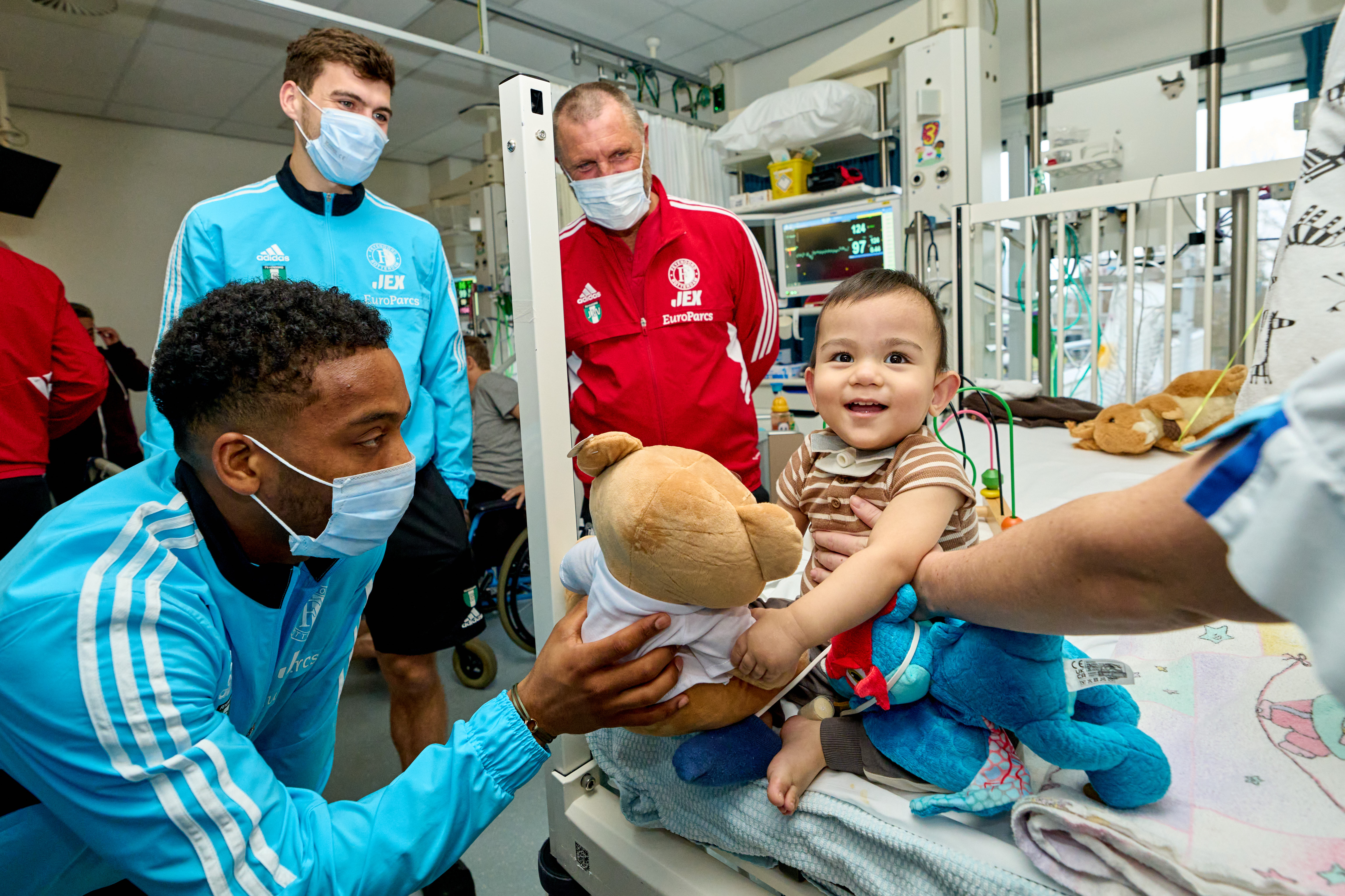 Quinten Timber geeft een knuffelbeer aan een jonge patiënt